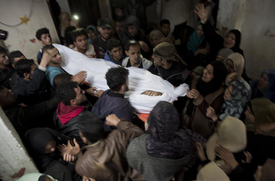 Relatives mourn over the body of 21-year-old Palestinian, Mohammed Saad, at the family home during his funeral in Gaza City, Saturday, March 30, 2019. Gaza's Health Ministry says Saad was shot dead by Israeli forces near the fence with Israel, hours before an expected mass protest there. (AP Photo/Khalil Hamra)