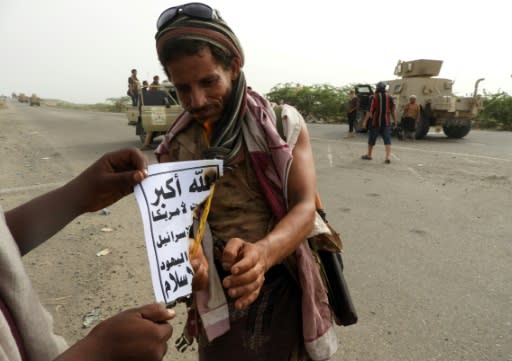 A Yemeni pro-government fighter burns a leaflet showing the banner of the Huthis which reads "God is the greatest... Death to America, death to Israel, cursed be the Jews, victory for Islam" in this picture taken at Al-Durayhimi on June 13, 2018