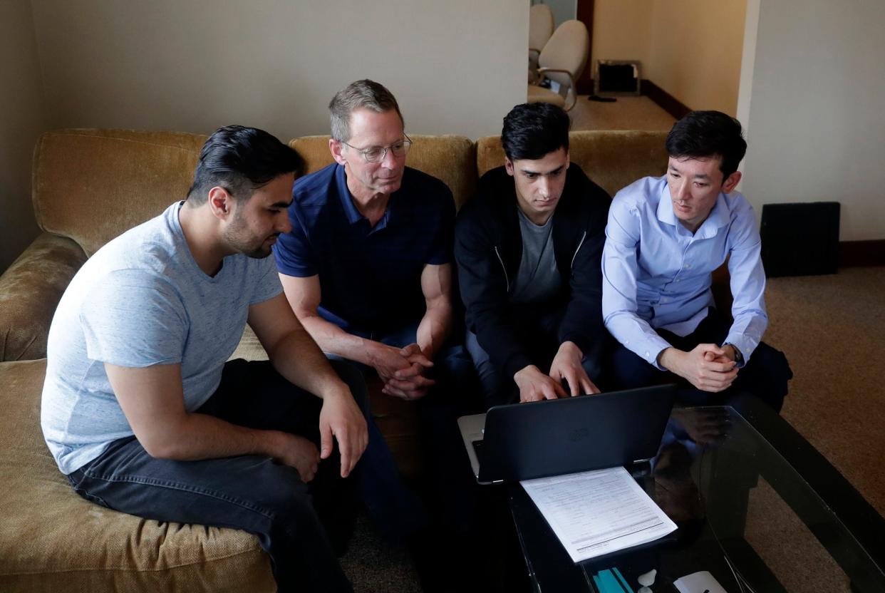 Mike Ruminski, second from left, helps Muddassir Saboory, Fayaz Nabizada and Ali Akbar Gholami work on the computer in their duplex on April 10, 2022, in Allouez, near Green Bay.