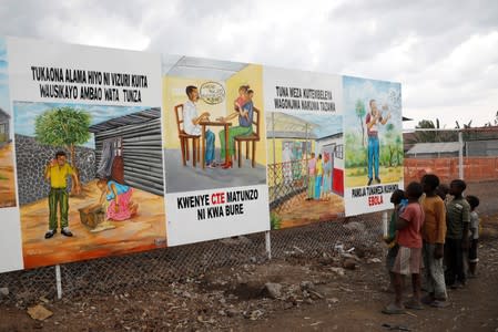 Children look at a billboard providing information about Ebola outside the newly constructed MSF Ebola treatment centre in Goma