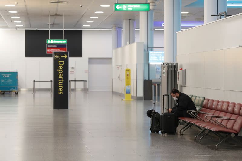 A passenger sits in an almost empty check-in area at Gatwick Airport, amid the coronavirus disease (COVID-19) outbreak, in Crawley