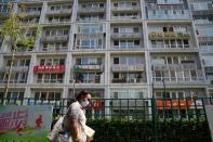 Woman wearing a face mask following the coronavirus disease (COVID-19) outbreak walks past a residential compound in Beijing