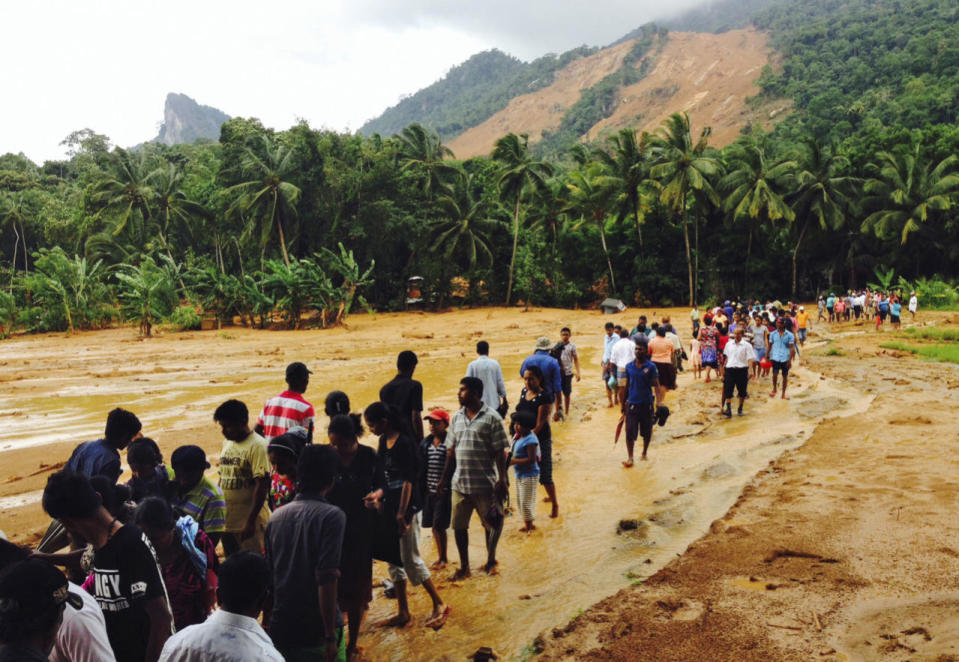 Sri Lankans walk on mud after a massive landslide at Aranayaka in Kegalle District, May 18, 2016. (AP Photo/Eranga Jayawardena)