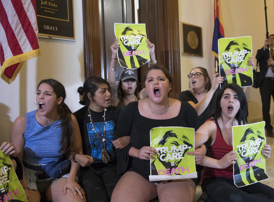 FILE - In this July 10, 2017, file photo, activists protest against the Republican health care bill outside the offices of Sen. Jeff Flake, R-Ariz., and Sen. Ted Cruz, R-Texas on Capitol Hill in Washington. About 120,000 Arizona residents who receive Medicaid benefits will have to get a job, do community service or temporarily lose health coverage. The Centers for Medicare and Medicaid Services approved the state's plan Friday, Jan.18, 2019. The Trump administration has urged states to consider changes to their Medicaid programs to encourage work and independence. Others say it unfairly targets the working class. (AP Photo/J. Scott Applewhite, File)