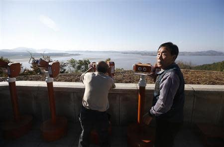 A man looks towards North Korea's propaganda village Kaepoong through a pair of binoculars at the Unification Observation Platform, near the demilitarized zone which separates the two Koreas, in Paju, north of Seoul October 16, 2013. REUTERS/Kim Hong-Ji