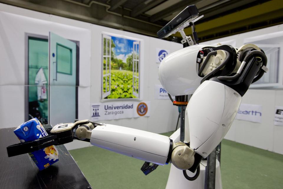 Amigo, a white robot the size of a person, uses information gathered by other robots to move towards a table to pick up a carton of milk and deliver it to an imaginary patient in a mock hospital room at the Technical University of Eindhoven, Netherlands, Wednesday Jan. 15, 2014. A group of five of Europe's top technical universities, together with technology conglomerate Royal Philips NV, are launching an open-source system dubbed "RoboEarth" Thursday. The heart of the mission is to accelerate the development of robots and robotic services via efficient communication with a network, or "cloud". (AP Photo/Peter Dejong)