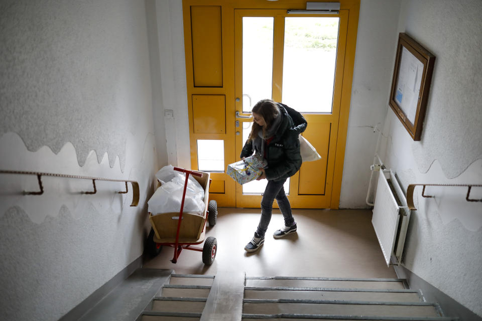 Social worker Rebekka Rauchhaus delivers goods in Berlin, Germany, Thursday, April 2, 2020. The group that provides help to about 1,300 poor families across Germany is now delivering food, hygiene products and children’s games to their doorstep during the coronavirus pandemic. (AP Photo/Markus Schreiber)