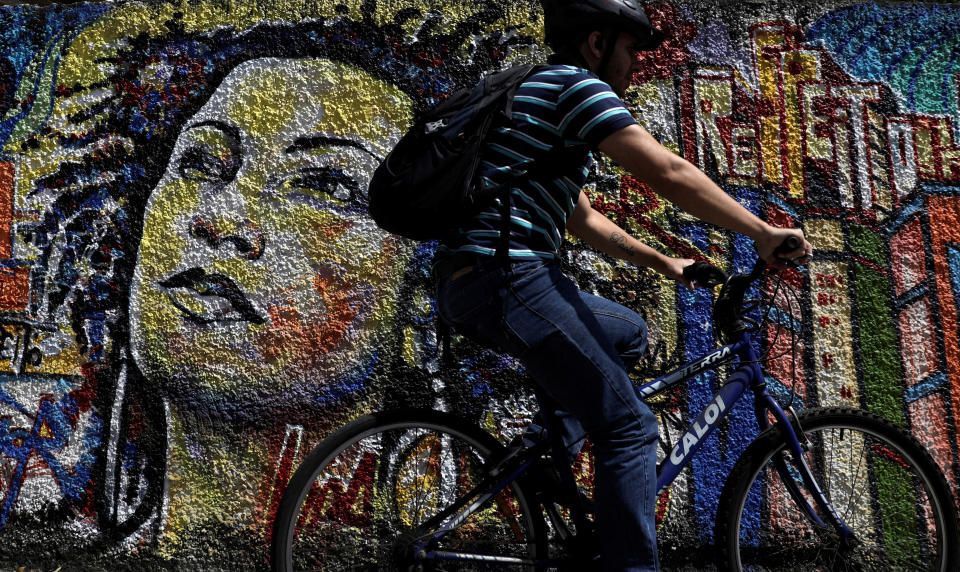 A man rides past a graffiti in tribute of late councilwoman Marielle Franco, murdered last year in Rio de Janeiro, Brazil April 18, 2019. REUTERS/Ricardo Moraes