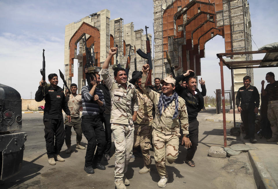 Iraqi security forces chant slogans against the Islamic State group after opening the main gate of their base that was closed for months in Tikrit, 80 miles  north of Baghdad, Iraq, Friday, April 3, 2015. (AP Photo/Khalid Mohammed)