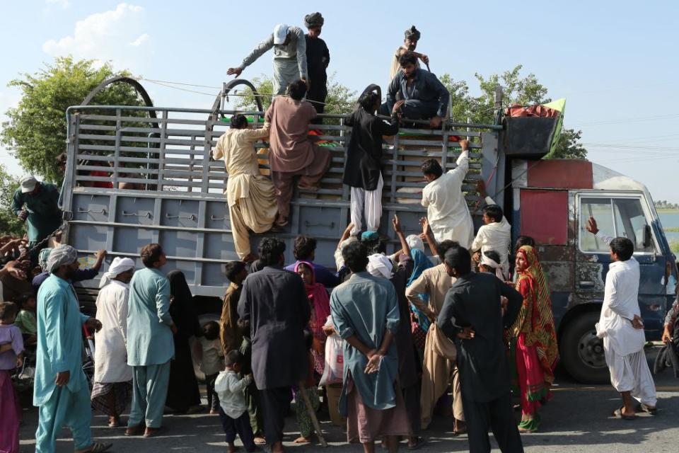 Internally displaced people on Aug. 29, 2022 climb on a truck to get food boxes from a relief team in a flood-hit area in Pakistan's Dera Ghazi Khan district of Punjab province.<span class="copyright">Shahid Saeed Mirza—AFP via Getty Images</span>