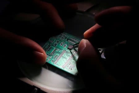 File Photo:: A researcher plants a semiconductor on an interface board which is placed under a microscope during a research work to design and develop a semiconductor product at Tsinghua Unigroup research centre in Beijing, China, February 29, 2016. REUTERS/Kim Kyung-Hoon/File Photo
