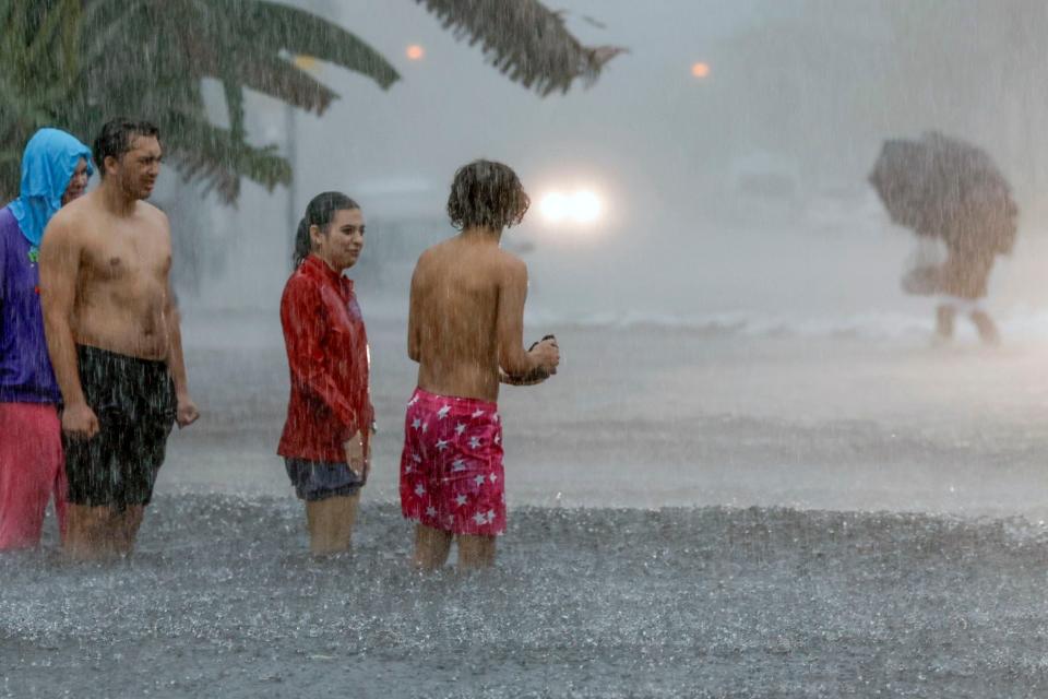 People attempt to cross a flooded street in Miami Beach, Fla., Wednesday, June 12, 2024. (Al Diaz/Miami Herald via AP)