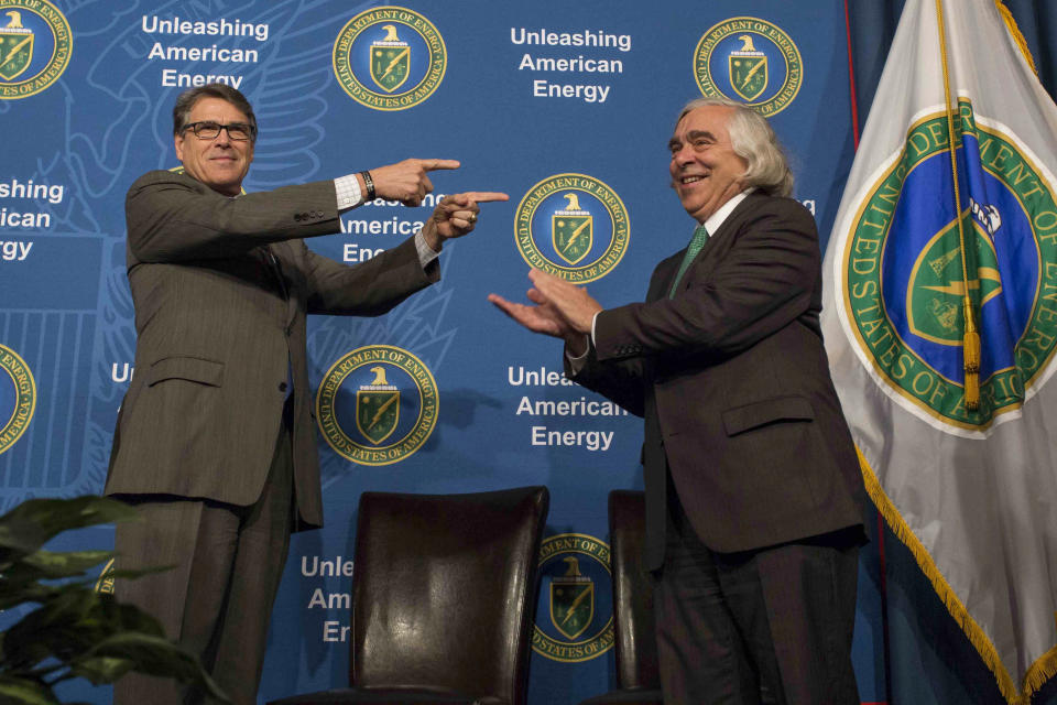 FILE - In this Aug. 2, 2018 photo made available by the U.S. Department of Energy, Energy Secretary Rick Perry welcoming his predecessor, Ernest Moniz, during the unveiling of Moniz's portrait. Since Donald Trump took office, America’s exports of liquid natural gas and crude oil have surged, rivaling the likes of Saudi Arabia and Russia. To achieve “energy dominance,” the Trump administration has taken its cues from an unlikely source: the Obama administration. (Simon Edelman/U.S. Department of Energy via AP)