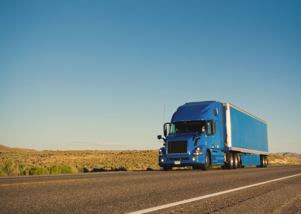 A large blue truck on a rural road. 