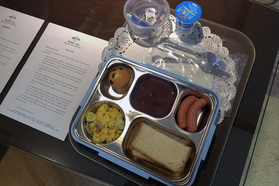 Breakfast in a sealed box, delivered by tray is placed next to a coronavirus prevention notice inside the hotel room which assigned for journalist who was selected to cover the opening ceremony of the Chinese People's Political Consultative Conference (CPPCC) in Beijing, Thursday, May 21, 2020. China is strictly limiting the number of journalists who can cover its ongoing legislative session because of the coronavirus outbreak. (AP Photo/Andy Wong)