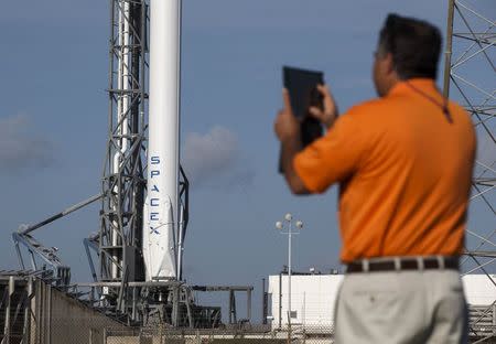 A NASA media escort takes a photo of the unmanned SpaceX Falcon 9 rocket with Dragon capsule as it sits on launch pad 40 at the Cape Canaveral Air Force Station in Cape Canaveral, Florida April 14, 2015. REUTERS/Scott Audette