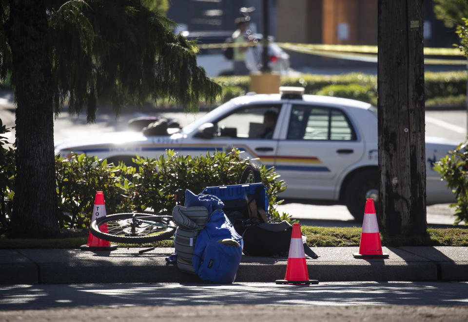 A bike and person's belongings are seen on the sidewalk behind police tape at the scene of a shooting in Langley, British Columbia, Monday, July 25, 2022. Canadian police reported multiple shootings of homeless people Monday in a Vancouver suburb and said a suspect was in custody. (Darryl Dyck/The Canadian Press via AP)