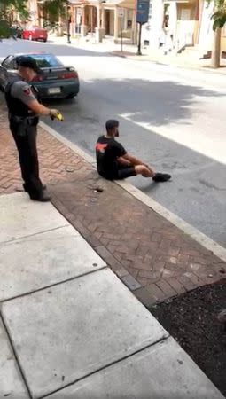 A man sits on a curb, moments before getting Tasered by a police officer, in Lancaster, Pennsylvania, U.S., June 28, 2018, in this still image taken from a video obtained from social media. MANDATORY CREDIT. Jay Jay/via REUTERS