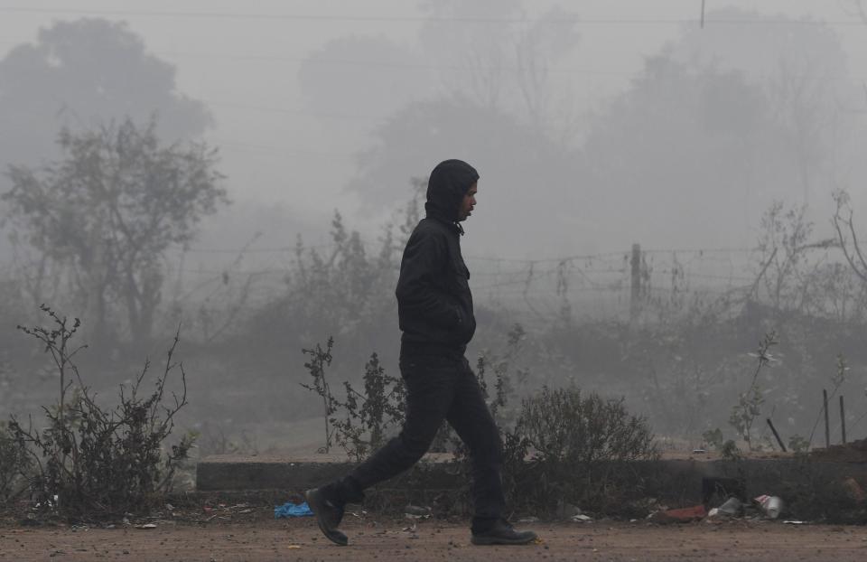 A man walks along a path amidst smog and fog conditions during a cold morning in Faridabad, India, on February 6, 2019. Smog levels spike during winter in north India, when air quality often eclipses the World Health Organization's safe levels.  / Credit: Money Sharma / AFP/Getty Images