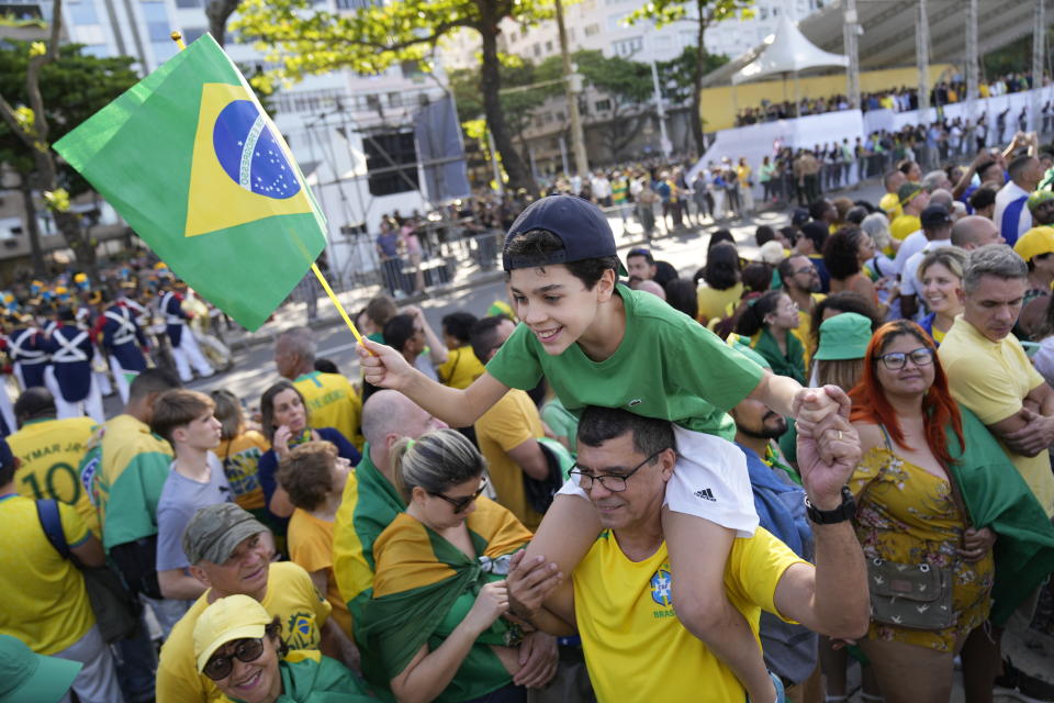A child rides on the shoulders of his father during a military display and rally called by President Jair Bolsonaro to celebrate the bicentennial of the country's independence from Portugal, in Rio de Janeiro, Brazil, Wednesday, Sept. 7, 2022. (AP Photo/Silvia Izquierdo)