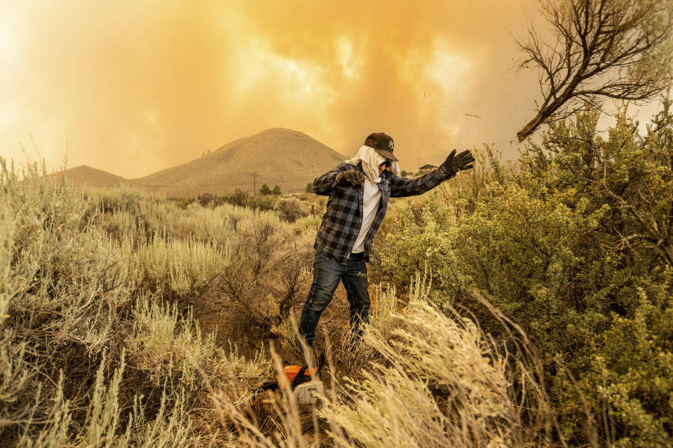 David Garfield clears a fire break around his home as the Sugar Fire, part of the Beckwourth Complex Fire, burns towards Doyle, Calif., on Saturday, July 10, 2021. (AP Photo/Noah Berger)