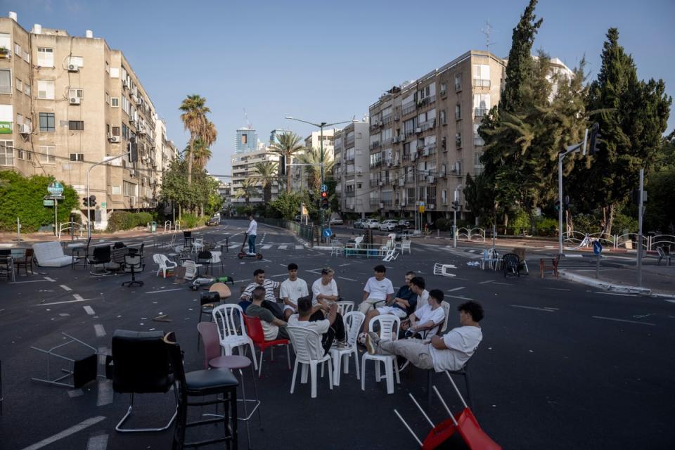 Israeli youths sit together at a junction on a car-free road during the Jewish holiday of Yom Kippur (AP)