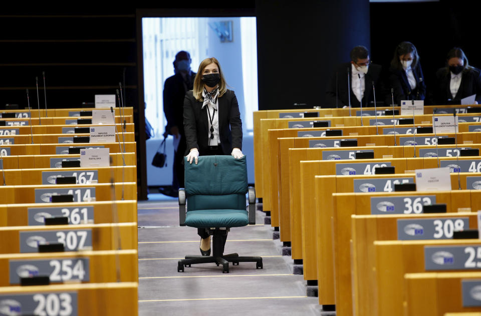 A parliamentary worker wheels a rolling chair down the aisle of the plenary chamber ahead of a debate on Turkey at the European Parliament in Brussels, Monday, April 26, 2021. (AP Photo/Olivier Matthys, Pool)