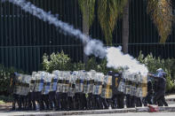 Riot police fire tear gas at Indigenous protesters outside Congress in Brasilia, Brazil, Tuesday, June 22, 2021. Indigenous who are camping in the capital to oppose a proposed bill they say would limit recognition of reservation lands clashed with police blocking them from entering Congress. (AP Photo/Eraldo Peres)