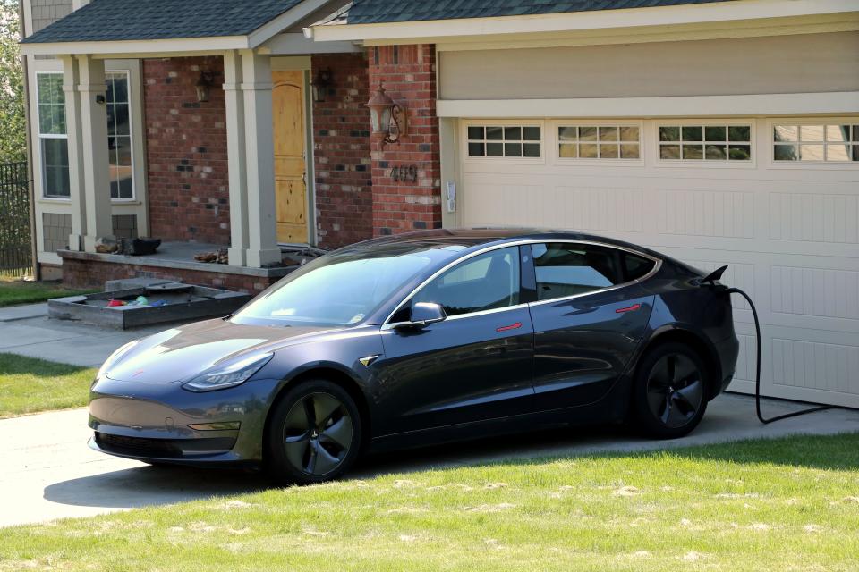 Tesla electric car in driveway being charged at a home with an EV charger in residential neighborhood, Moscow, Idaho. (Photo by: Don & Melinda Crawford/UCG/Universal Images Group via Getty Images)