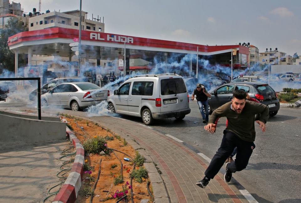 <p>Palestinians run away from tear gas shot at them by Israeli forces during a protest in Ramallah, in the occupied West Bank, on May 15, 2018. (Photo: Abbas Momani/AFP/Getty Images) </p>