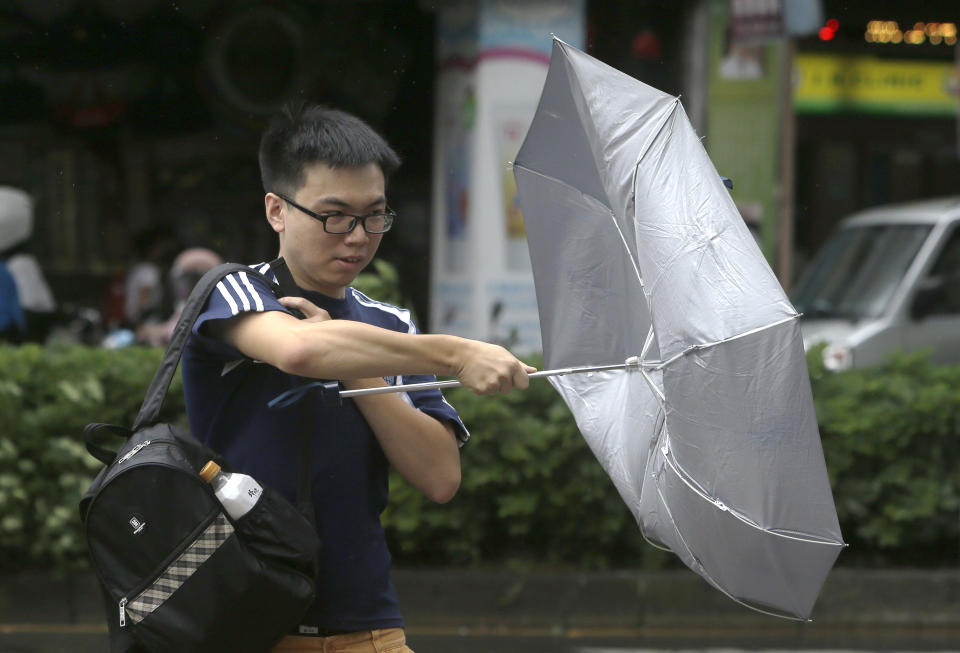 A man struggles with his umbrella against powerful gusts of wind generated by typhoon Ineng in Taipei, Taiwan, Saturday, Aug. 24, 2019. (AP Photo/Chiang Ying-ying)