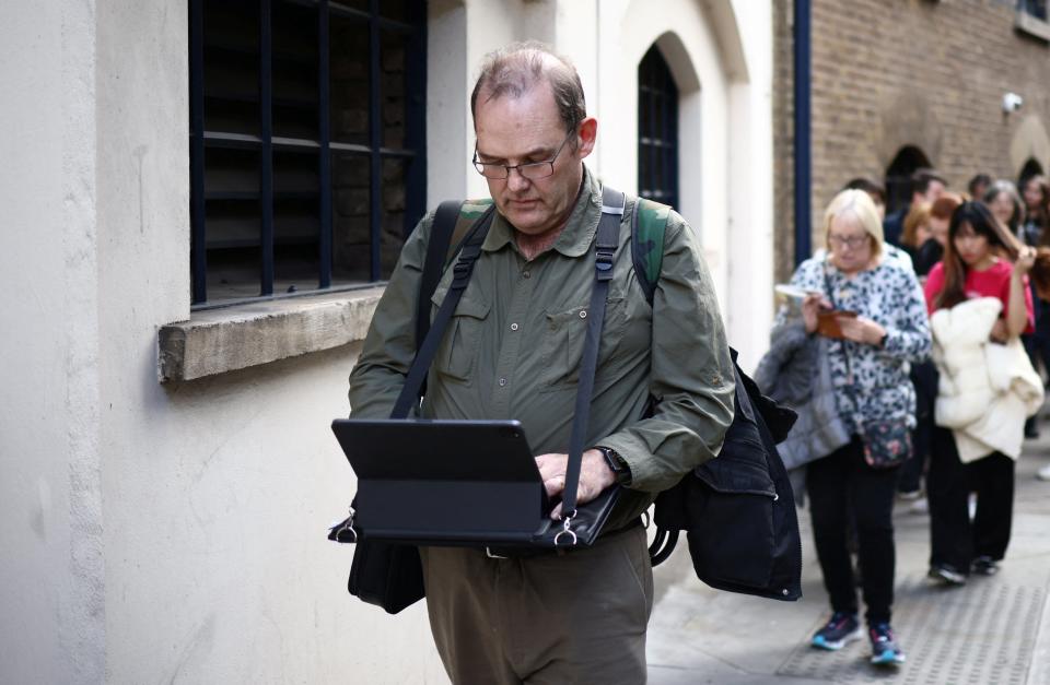 Stuart Murphy works on his iPad as he stands in a queue near Bermondsey to pay his respects (REUTERS)