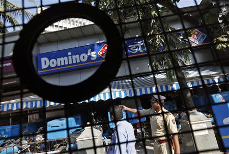 A policeman (R) talks to an employee of a Dominos Pizza outlet after it was ransacked by activists of the Republican Party of India (RPI) in a Mumbai suburb December 20, 2013. REUTERS/Mansi Thapliyal