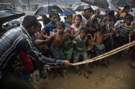 <p>A man hits anxious Rohingya children with a cane as things get out of control during a humanitarian aid distribution while monsoon rains continue to batter the area causing more difficulties on October 7, Thainkhali camp, Cox’s Bazar, Bangladesh. (Photograph by Paula Bronstein/Getty Images) </p>