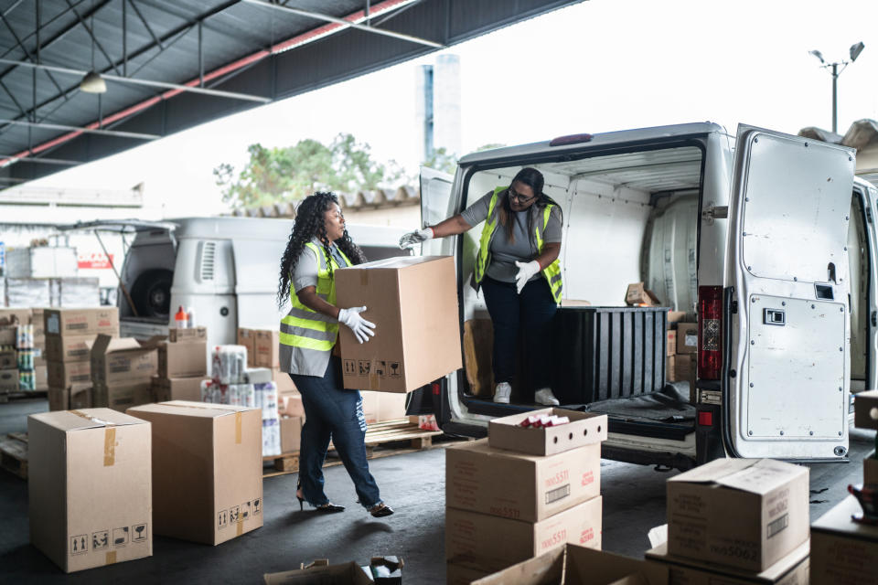 Two women are loading boxes into a van