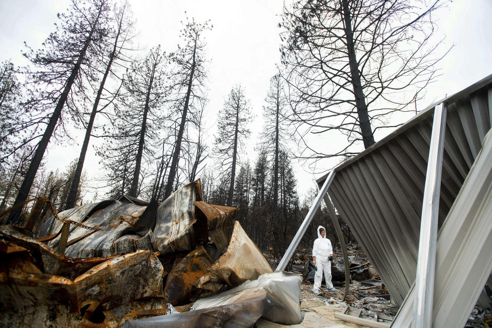 In this Feb. 8, 2019, photo, Carol Mendes-Klint pauses while helping a friend comb through the remains of her residence, destroyed by the Camp Fire, in Paradise, Calif. In the 100 days since a wildfire nearly burned the town of Paradise off the map, the long recovery is just starting. Work crews have been cutting down trees and clearing burned-out lots, but Paradise is mostly a ghost town where survivors still dig for keepsakes in the foundations of their homes. (AP Photo/Noah Berger)