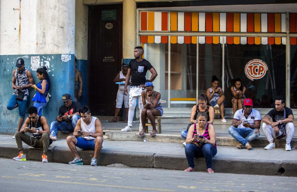 In this Jan. 6, 2017 photo, people use a public wifi hotspot in Havana, Cuba. Home internet came to Cuba in December 2016, in a limited pilot program that’s part of the most dramatic change in daily life here since the declaration of detente with the United States on Dec. 17, 2014. (AP Photo/Desmond Boylan)