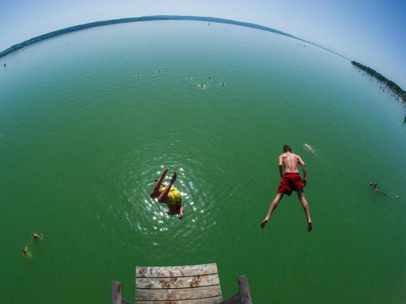 Zwei Männer springen in Utting am Ammersee vom Sprungbrett. Foto: Marc Müller