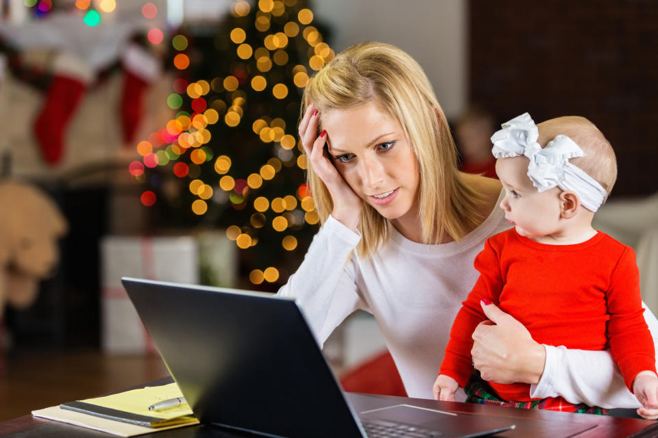 busy mum at computer holding daughter at Christmas