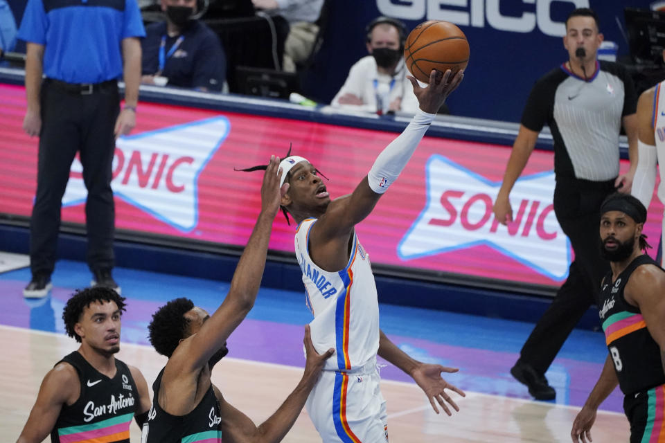 Oklahoma City Thunder guard Shai Gilgeous-Alexander shoots between San Antonio Spurs guard Tre Jones, left, forward Trey Lyles, second from left, and guard Patty Mills, right, during the second half of an NBA basketball game Wednesday, Feb. 24, 2021, in Oklahoma City. (AP Photo/Sue Ogrocki)