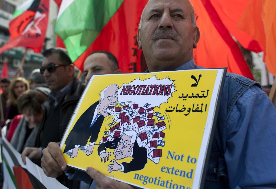 A Palestinian protester holds a placard with a drawing depicting Palestinian President Mahmoud Abbas and Israeli Prime Minister Benjamin Netanyahu during an anti-peace talks rally in the West Bank city of Ramallah, Wednesday, March 19, 2014. The Palestinians on Wednesday threatened to resume their campaign for international recognition at the United Nations if Israel calls off a planned release of Palestinian prisoners, deepening a crisis that has threatened to derail U.S.-led Mideast peace efforts. (AP Photo/Nasser Nasser)