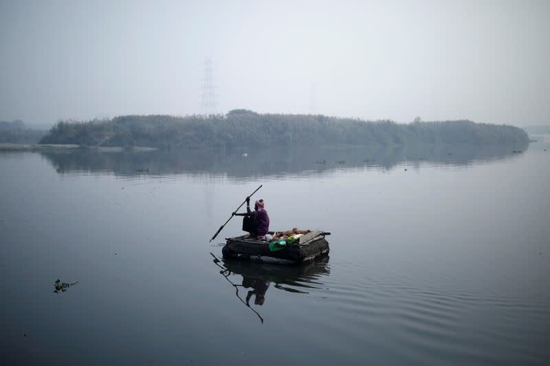 A man rows a makeshift boat across Yamuna river on a smoggy morning in New Delhi