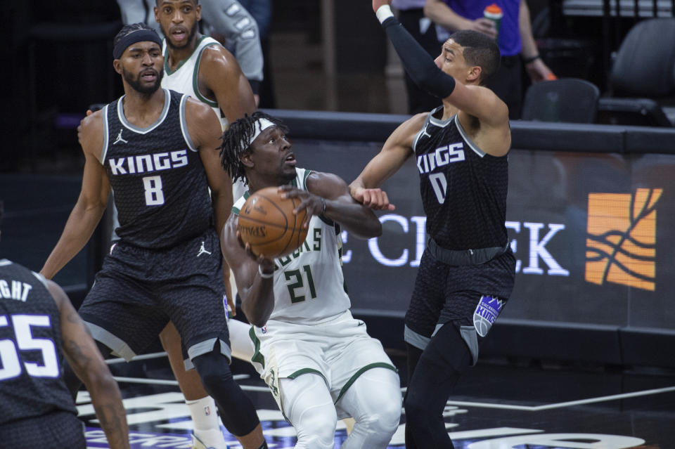 Sacramento Kings forward Maurice Harkless (8) and guard Tyrese Haliburton (0) defend against Milwaukee Bucks guard Jrue Holiday (21) during the first quarter of an NBA basketball game in Sacramento, Calif., Saturday, April 3, 2021. (AP Photo/Randall Benton)