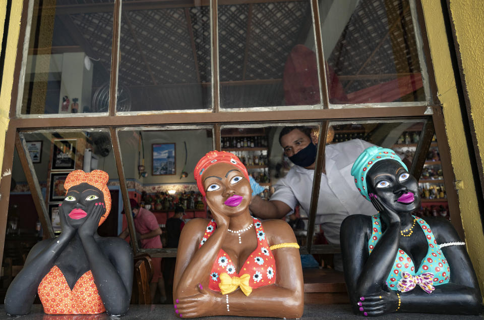 Un empleado de restaurante utiliza una mascarilla mientras limpia las ventanas para la reapertura del lugar durante la pandemia de COVID-19 en Sao Paulo, Brasil, el lunes 6 de julio de 2020. Bares, restaurantes y estéticas pueden reanudar sus operaciones desde el lunes luego de tres meses de cuarentena, y se requiere que cumplan con medidas preventivas y horarios restringidos. (AP Foto/Andre Penner)