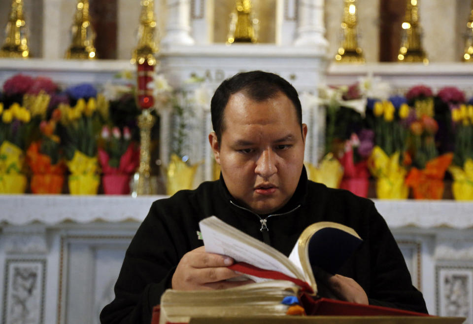 In this April 19, 2020, photo, the Rev. Joseph Dutan, 32, prepares for a virtual Sunday Mass livestreamed from St. Brigid Church in the Brooklyn borough of New York. Over the past month, Rev. Dutan has lost his mentor and fellow priest, as well as his father, to the coronavirus. (AP Photo/Jessie Wardarski)