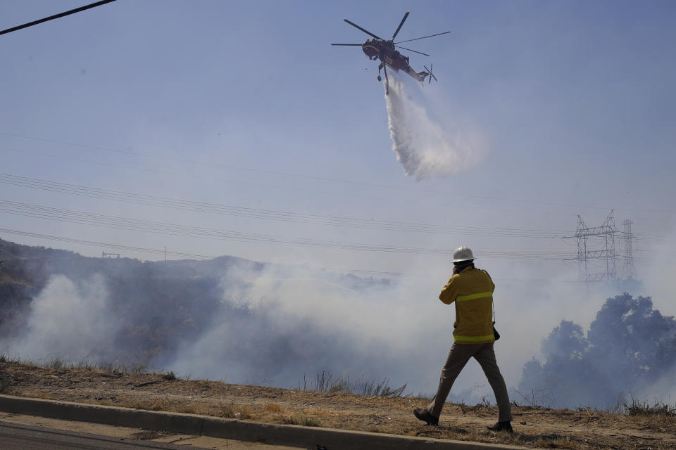 FILE - In this Aug. 3, 2020, file photo, a newspaper photographer takes photos of a helicopter making a water drop on the Elsmere wildfire, in Santa Clarita, Calif. Journalists have captured searing, intimate images of active and dangerous wildfires burning California, due in large part to a state law that guarantees press virtually unfettered access to disaster sites. That’s not the case everywhere as rules about media access vary by state, and even by government agency. (AP Photo/Marcio Jose Sanchez, File)