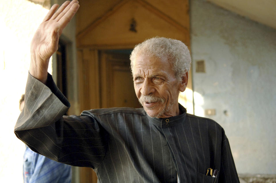 FILE - In this Sunday, May 21, 2006 file photo, renowned Egyptian poet Ahmed Fouad Negm returns the greetings of a neighbor, outside his home in Cairo, Egypt. State media says Egypt’s best known satirical poet, Ahmed Fouad Negm, has died at 84, early on Tuesday. Known as the “poet of the people,” Negm’s use of colloquial Egyptian Arabic has endeared him to his countrymen. He shot to fame in the 1970s when his poetry, written in Egypt’s colloquial Arabic, was sung by blind musician Sheik Imam, allowing both to inspire generations of youth aspiring for change. (AP Photo/Mohamed Al-Sehety, File)