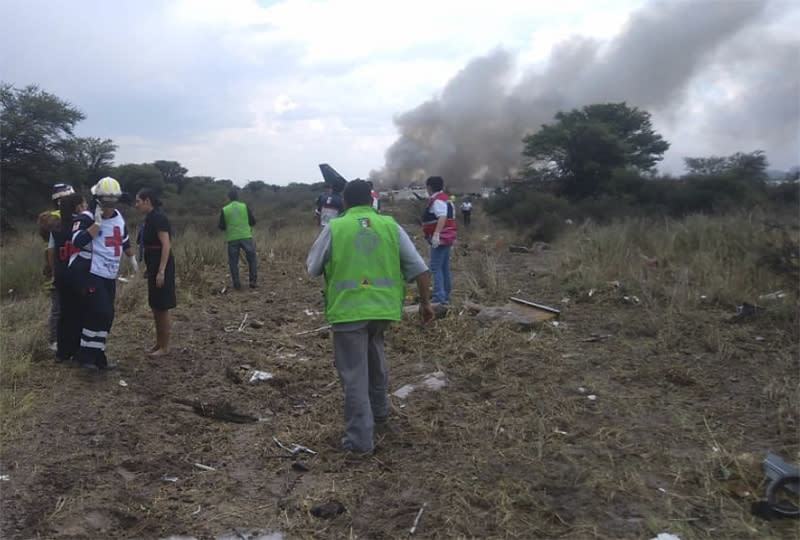 Rescue workers and firefighters are seen at the site where an Aeromexico airliner has suffered an "accident" in a field near the airport of Durango, Mexico, Tuesday, July 31, 2018. (Civil Defense Office of Durango Photo via AP)