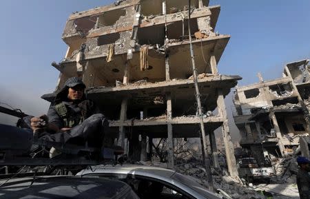 A Syrian army soldier sits with a cigarette next to a destroyed building in al-Hajar al-Aswad, Syria May 21, 2018. REUTERS/Omar Sanadiki/Files