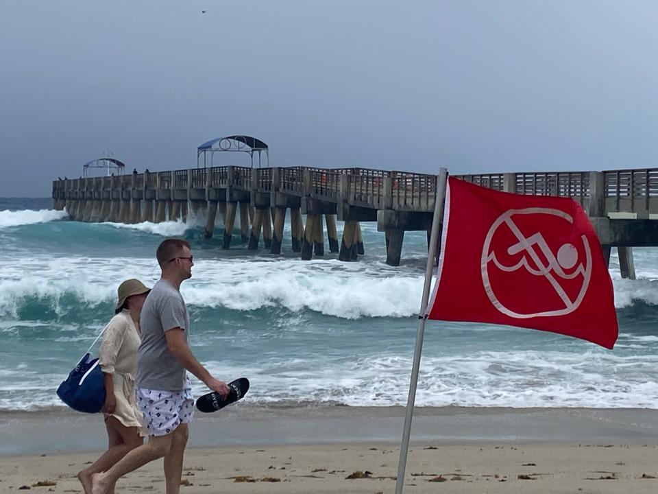 Red warning flags warning of rip currents flap in the 15-20 mph north winds on Palm Beach County beaches Wednesday.